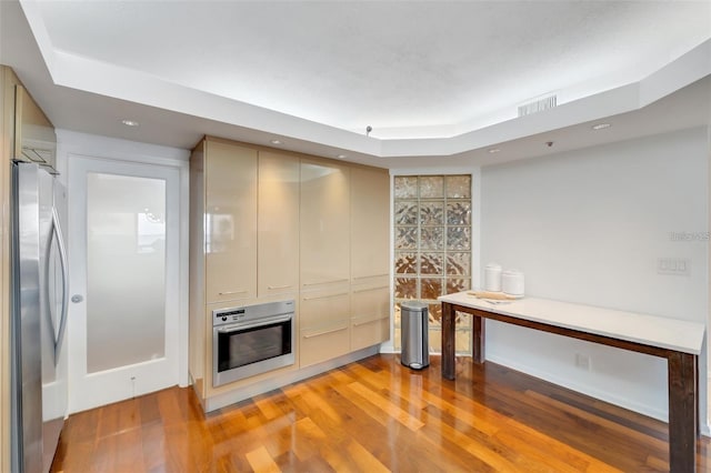 kitchen featuring light wood-type flooring, appliances with stainless steel finishes, and a tray ceiling