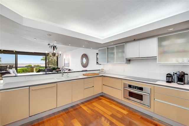 kitchen with sink, a notable chandelier, oven, black electric stovetop, and light wood-type flooring