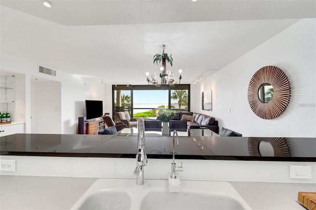 kitchen with white cabinets, a notable chandelier, and sink