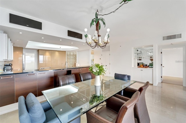 dining space featuring a notable chandelier, a raised ceiling, and light tile patterned floors