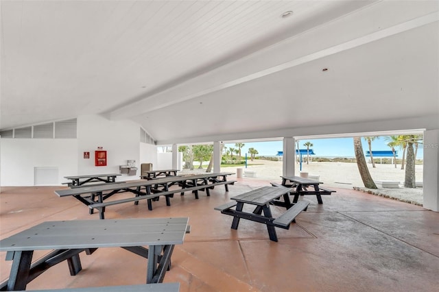 interior space featuring vaulted ceiling with beams, a water view, and concrete flooring