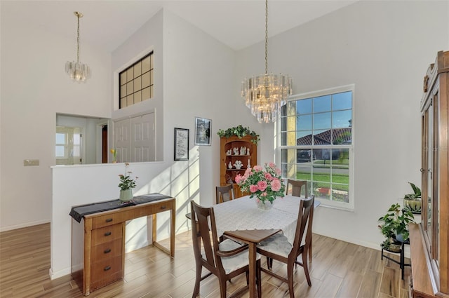 dining space with a high ceiling, hardwood / wood-style floors, and an inviting chandelier