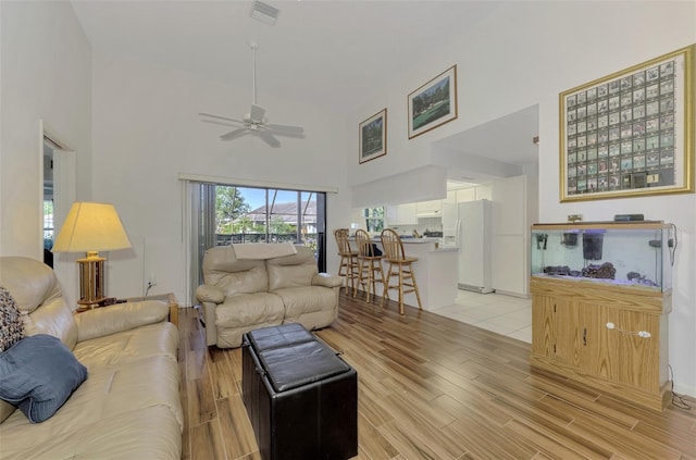 living room with ceiling fan and a towering ceiling