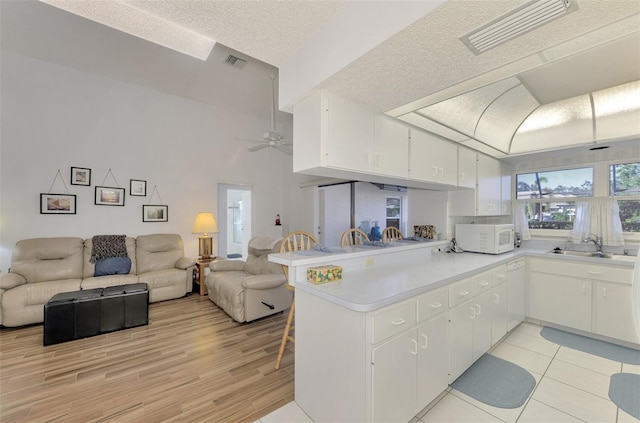 kitchen featuring white cabinetry, sink, white appliances, and kitchen peninsula