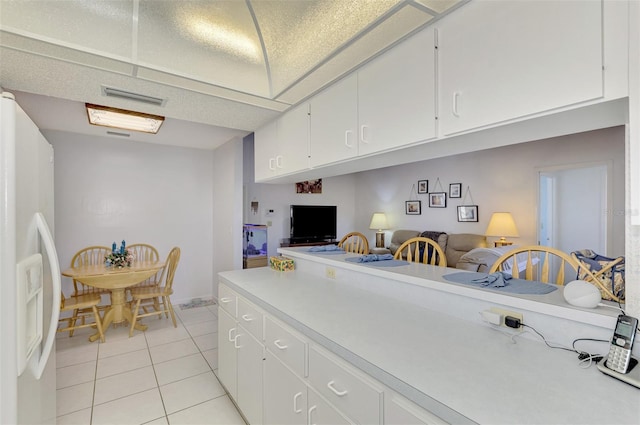 kitchen featuring light tile patterned flooring, white refrigerator with ice dispenser, and white cabinets