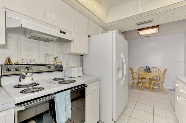 kitchen with light tile patterned flooring, white cabinets, white fridge with ice dispenser, and electric range