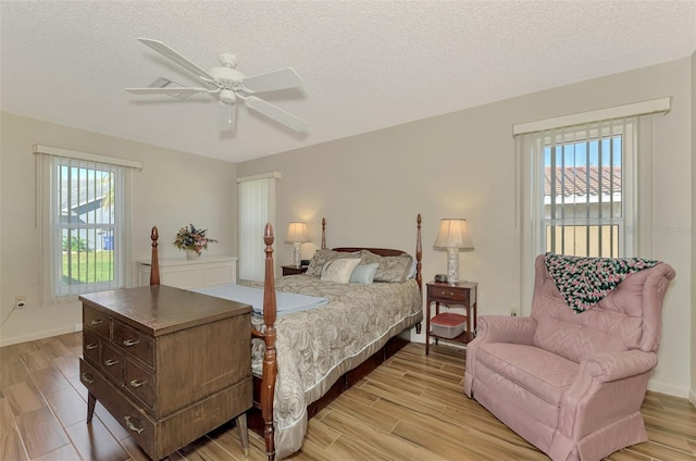 bedroom with multiple windows, a textured ceiling, and ceiling fan