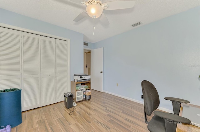 office with a textured ceiling, ceiling fan, and light wood-type flooring