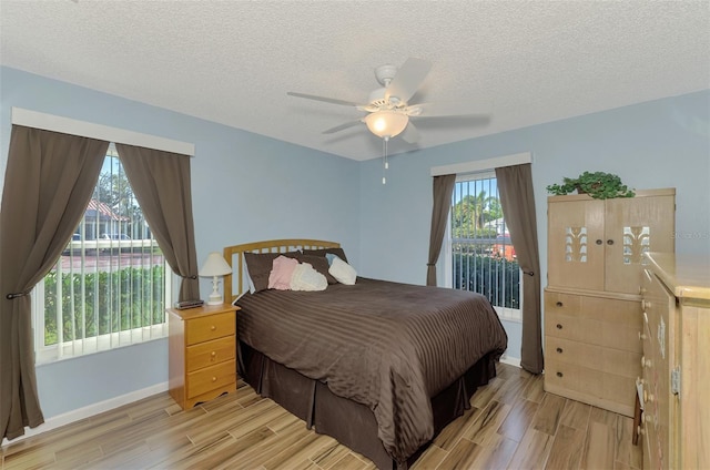 bedroom featuring ceiling fan, light hardwood / wood-style flooring, and a textured ceiling