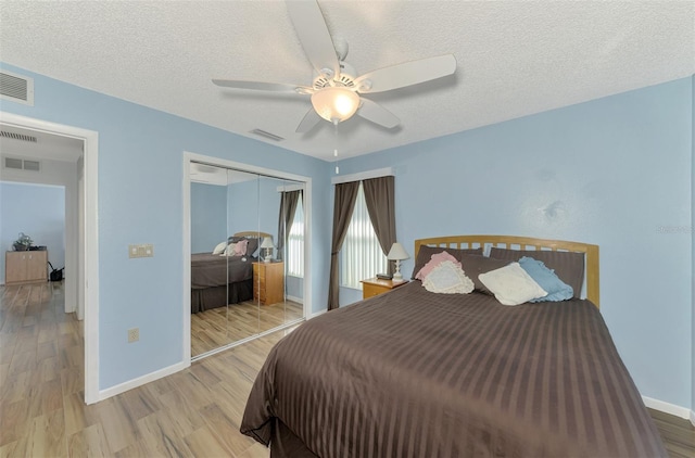 bedroom featuring ceiling fan, a textured ceiling, a closet, and light wood-type flooring