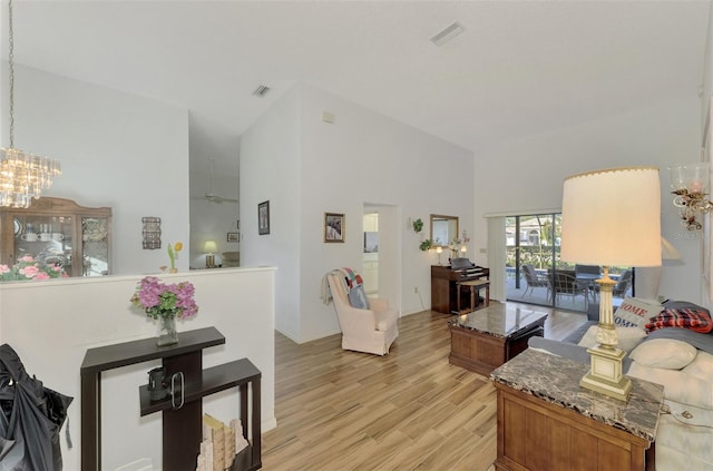 living room featuring a notable chandelier, light hardwood / wood-style flooring, and a high ceiling