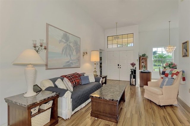 living room with a high ceiling, a chandelier, and light hardwood / wood-style flooring