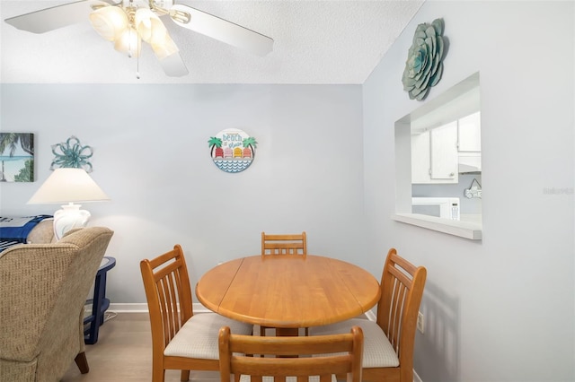 dining area featuring ceiling fan, light hardwood / wood-style floors, and a textured ceiling