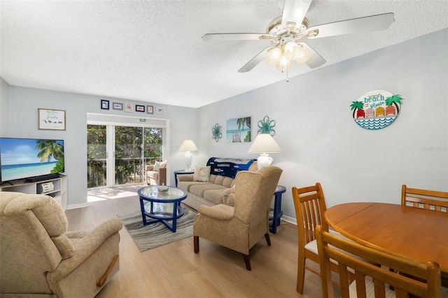 living room with ceiling fan, a textured ceiling, and light hardwood / wood-style flooring