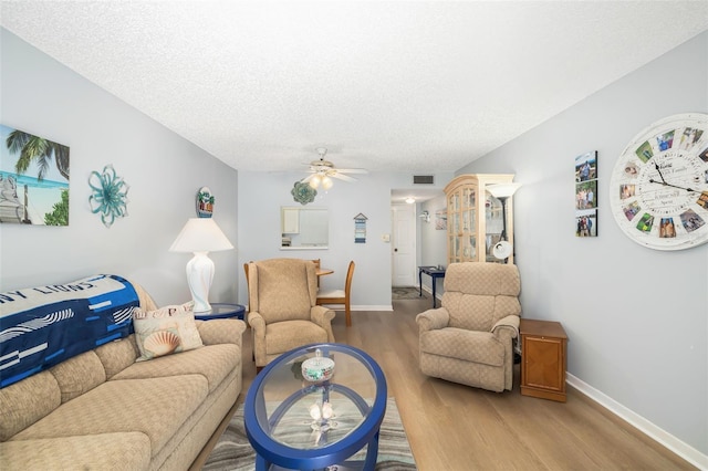 living room featuring ceiling fan, wood-type flooring, and a textured ceiling