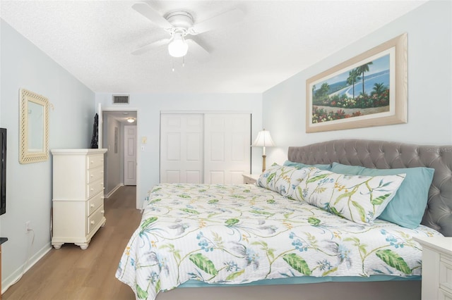 bedroom featuring ceiling fan, a closet, hardwood / wood-style floors, and a textured ceiling