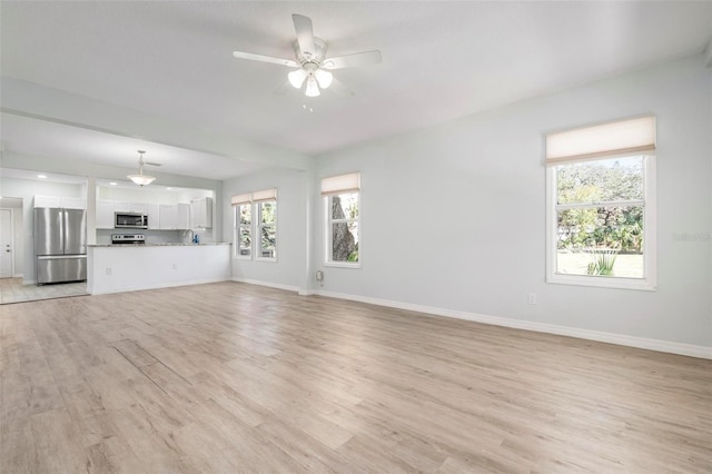 unfurnished living room featuring ceiling fan, light wood-style floors, and baseboards