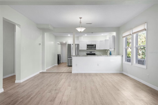 kitchen with baseboards, appliances with stainless steel finishes, light wood-style flooring, and white cabinets