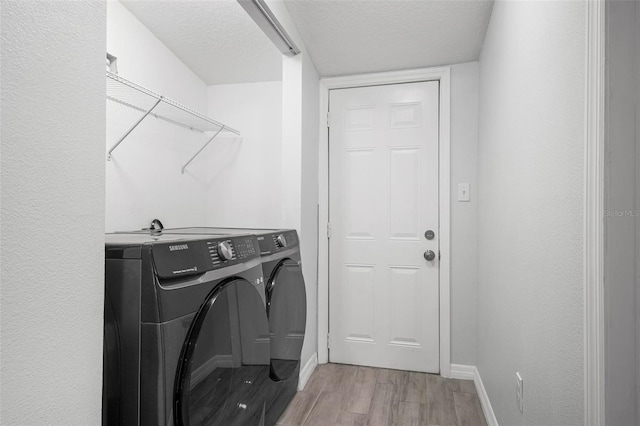 laundry room with a textured ceiling, baseboards, washing machine and dryer, and light wood-style floors