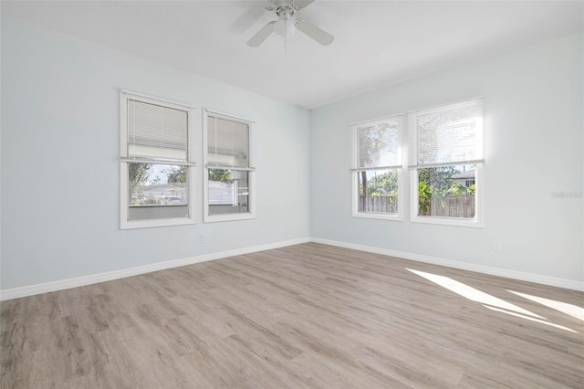 spare room featuring ceiling fan, light wood finished floors, and baseboards