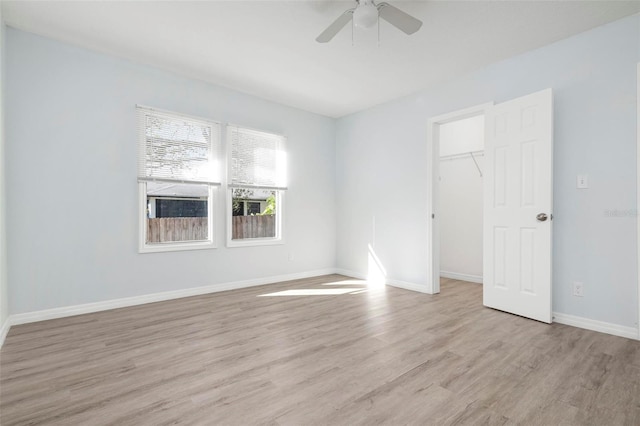 empty room featuring light wood-style floors, baseboards, and a ceiling fan