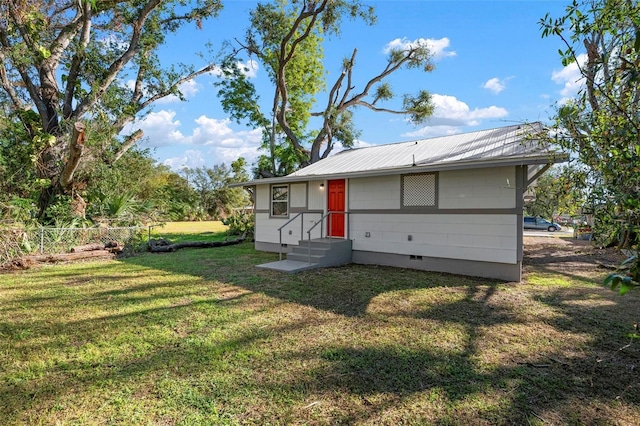 exterior space featuring a lawn, entry steps, crawl space, fence, and metal roof