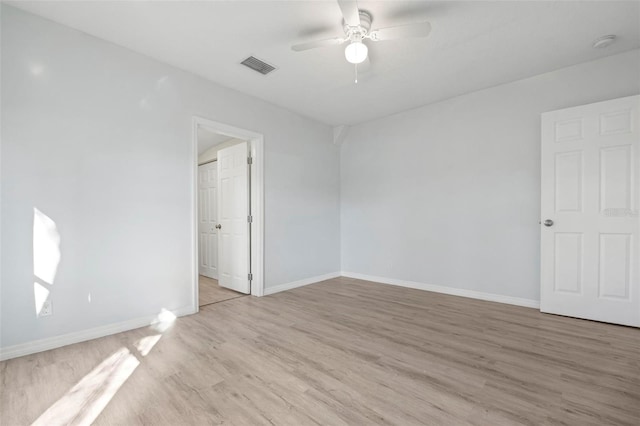 spare room featuring light wood-style floors, visible vents, ceiling fan, and baseboards