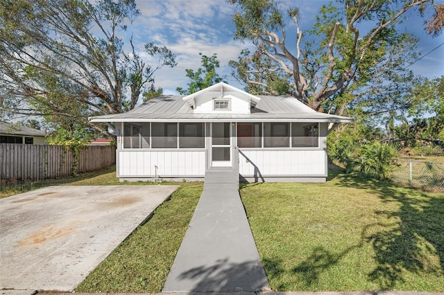 view of front of property with metal roof, a front yard, fence, and a sunroom