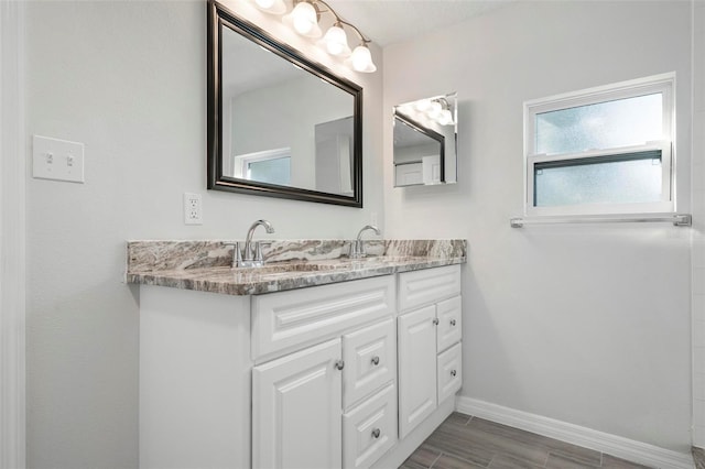 full bathroom with wood tiled floor, a sink, baseboards, and double vanity