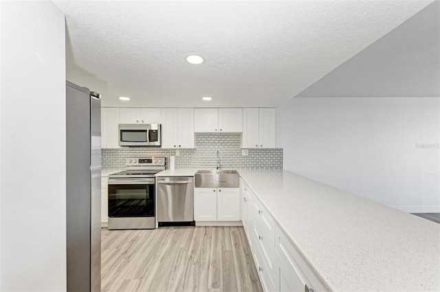 kitchen featuring stainless steel appliances, white cabinetry, tasteful backsplash, and sink