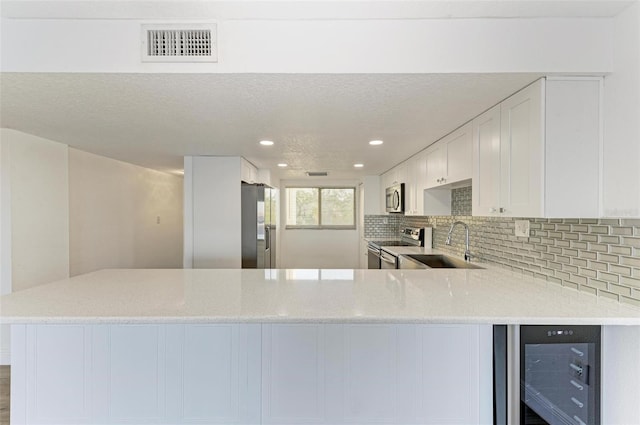 kitchen featuring kitchen peninsula, white cabinets, and stainless steel appliances