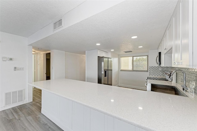 kitchen featuring kitchen peninsula, stainless steel appliances, and white cabinets