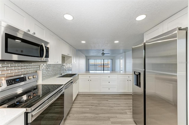 kitchen with appliances with stainless steel finishes, a textured ceiling, white cabinetry, and ceiling fan