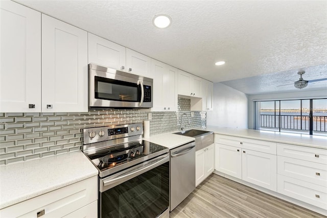 kitchen featuring white cabinets, sink, ceiling fan, a textured ceiling, and appliances with stainless steel finishes