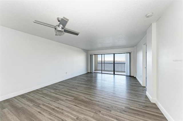 empty room with a textured ceiling, dark hardwood / wood-style floors, and ceiling fan