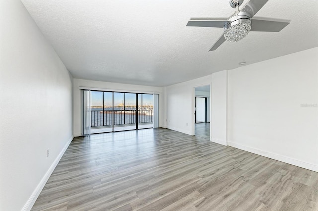 spare room with ceiling fan, light wood-type flooring, and a textured ceiling