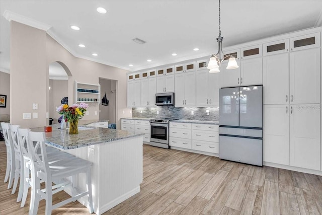 kitchen with light stone countertops, pendant lighting, decorative backsplash, white cabinets, and appliances with stainless steel finishes