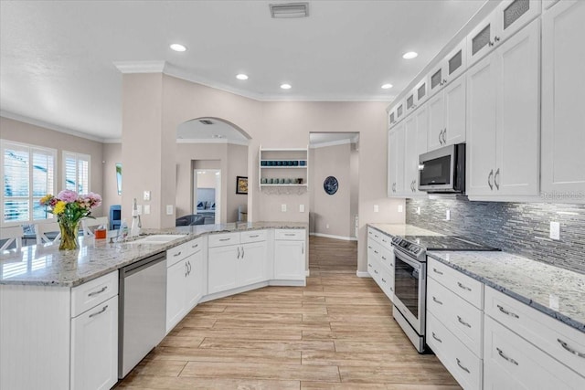 kitchen with appliances with stainless steel finishes, ornamental molding, light stone counters, decorative backsplash, and white cabinetry