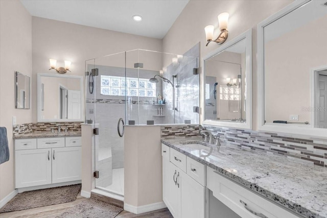 bathroom featuring walk in shower, hardwood / wood-style floors, backsplash, and vanity