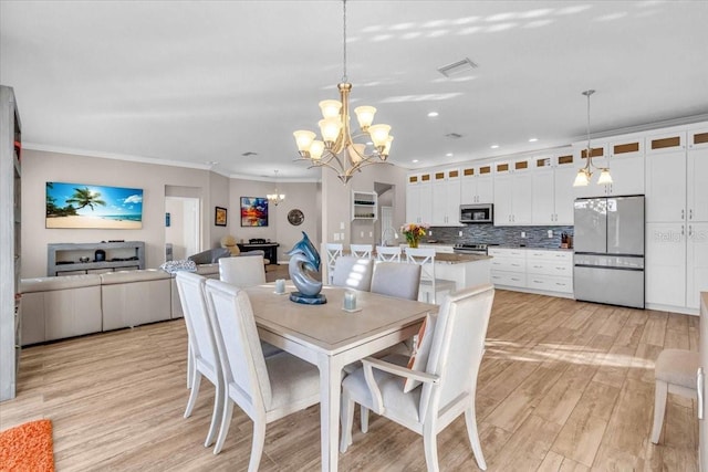 dining area with light wood-type flooring, crown molding, and a chandelier