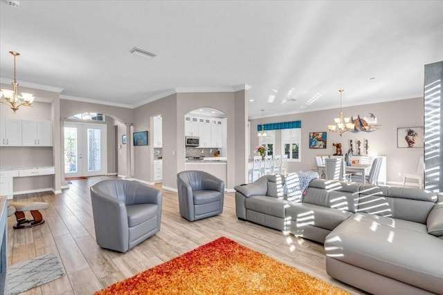 living room with an inviting chandelier, light wood-type flooring, and a healthy amount of sunlight