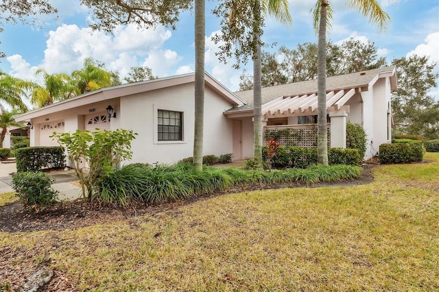 exterior space featuring stucco siding, an attached garage, and a lawn