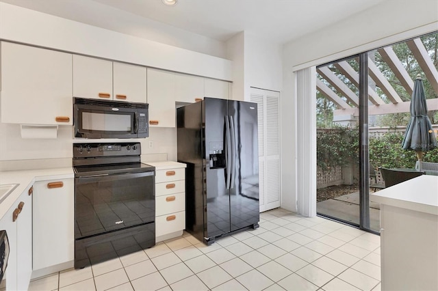 kitchen with light tile patterned floors, black appliances, white cabinets, and light countertops