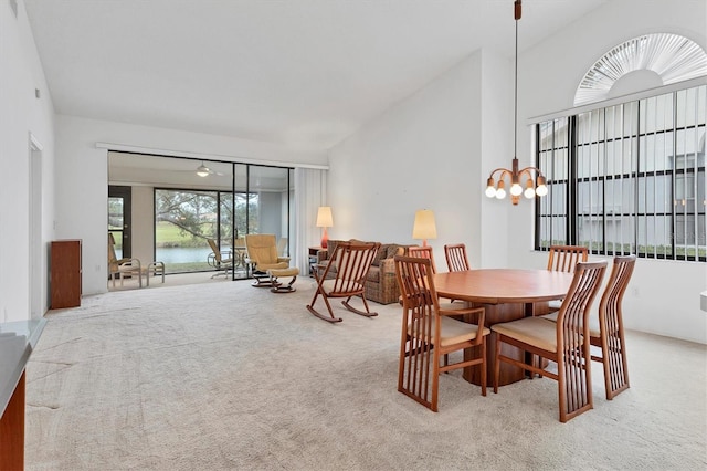 dining room featuring light colored carpet, lofted ceiling, and a notable chandelier