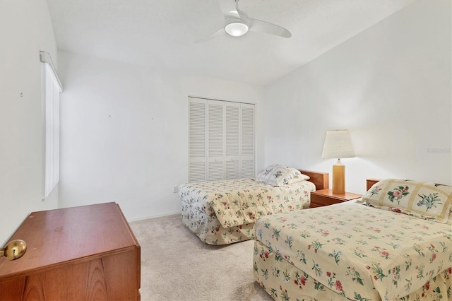 bedroom featuring a closet, light colored carpet, and a ceiling fan