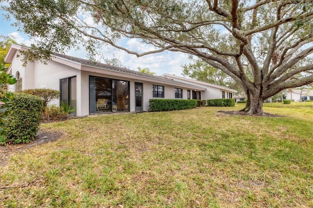 rear view of property with a yard and stucco siding