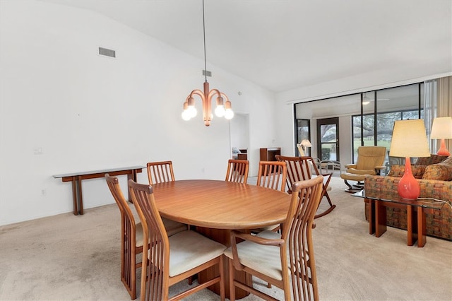 dining room featuring light colored carpet, lofted ceiling, and a chandelier