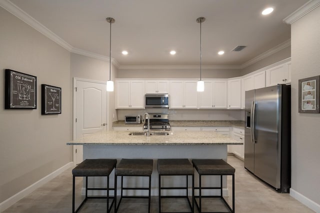 kitchen with white cabinets, decorative light fixtures, stainless steel appliances, and an island with sink