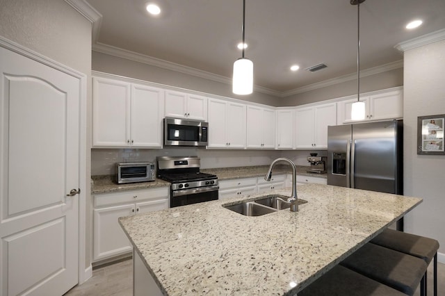 kitchen with white cabinets, sink, hanging light fixtures, an island with sink, and stainless steel appliances