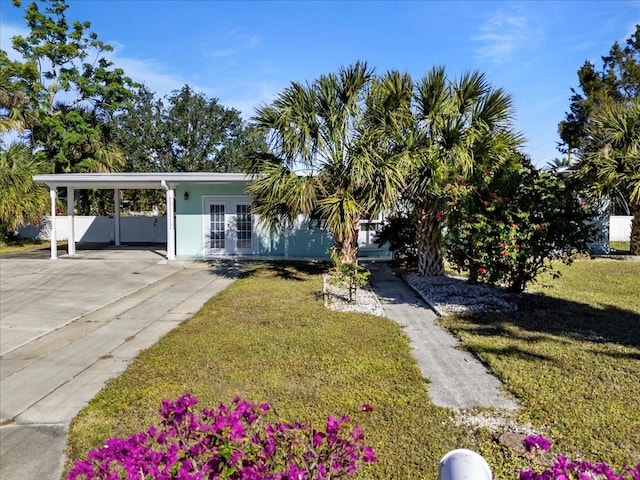 view of front of home with french doors, a carport, and a front lawn